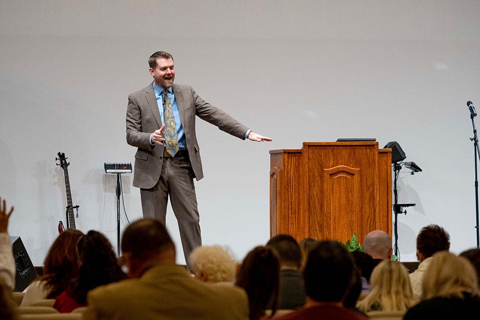 Pastor Tim Stahlman Preaching at Pulpit with Hand Raised During Service at Family Church Jamestown NY